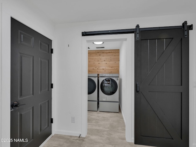 389 N Laramy Ln, Parks, AZ 86018 - washroom featuring washer and clothes dryer, baseboards, a barn door, and light wood-style flooring