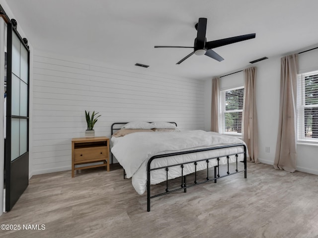 389 N Laramy Ln, Parks, AZ 86018 - bedroom featuring a barn door, multiple windows, light wood-style floors, and wooden walls
