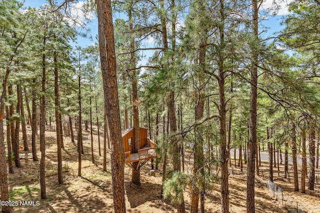 view of yard with a wooded view and a deck