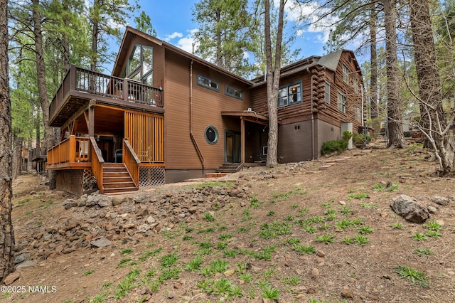 rear view of property featuring an attached garage and a wooden deck
