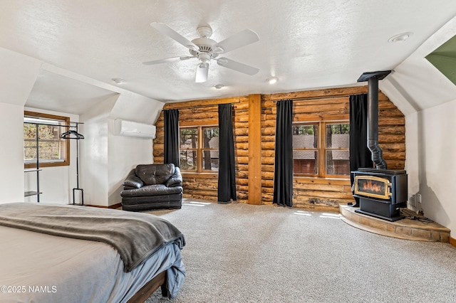 carpeted bedroom with a wood stove, an AC wall unit, a textured ceiling, a ceiling fan, and rustic walls