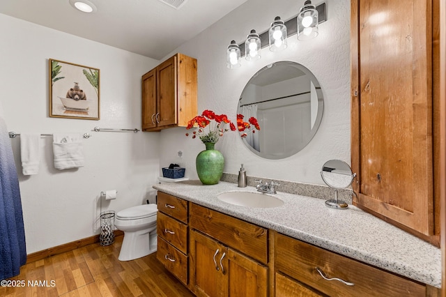 bathroom with vanity, baseboards, toilet, and wood finished floors