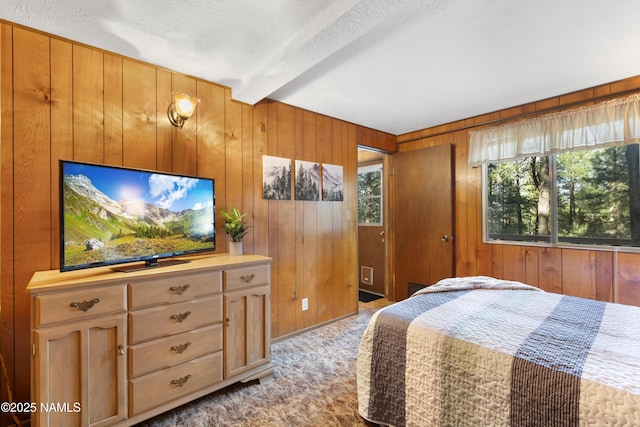 bedroom featuring wooden walls, carpet flooring, and beam ceiling