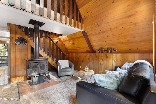 living area featuring lofted ceiling, wood ceiling, wooden walls, and a wood stove
