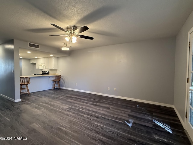 unfurnished living room with ceiling fan, a textured ceiling, and dark hardwood / wood-style flooring