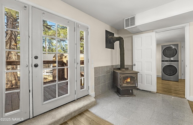 4573 Canyon Loop, Flagstaff, AZ 86005 - unfurnished living room featuring stacked washing machine and dryer, a wood stove, french doors, tile walls, and wainscoting