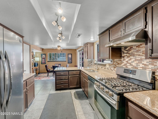 3114 N Connor St, Flagstaff, AZ 86004 - kitchen with stainless steel appliances, under cabinet range hood, backsplash, a peninsula, and light tile patterned flooring