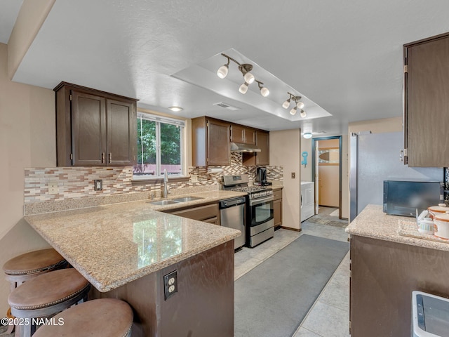 3114 N Connor St, Flagstaff, AZ 86004 - kitchen with stainless steel appliances, a raised ceiling, under cabinet range hood, backsplash, and a peninsula