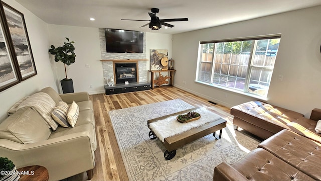 living room featuring a large fireplace, ceiling fan, and light hardwood / wood-style floors