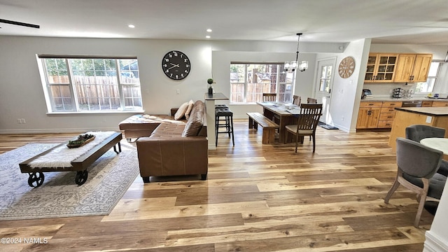 living room with a notable chandelier, a wealth of natural light, and light hardwood / wood-style flooring