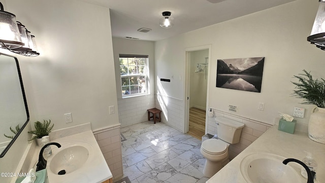 bathroom with vanity, toilet, and tile walls