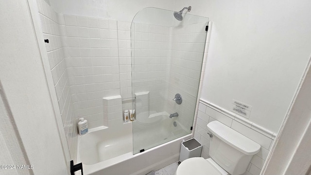 bathroom featuring toilet, shower / bathing tub combination, and tile walls