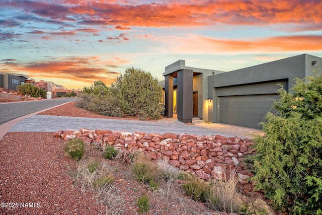 modern home with decorative driveway, a garage, and stucco siding