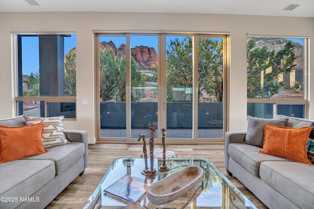 living room featuring visible vents, wood finished floors, and a healthy amount of sunlight