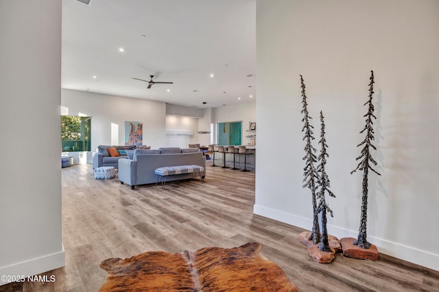 living area featuring recessed lighting, a ceiling fan, wood finished floors, and baseboards