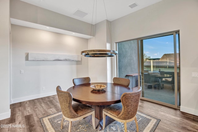 dining area with baseboards, visible vents, and wood finished floors