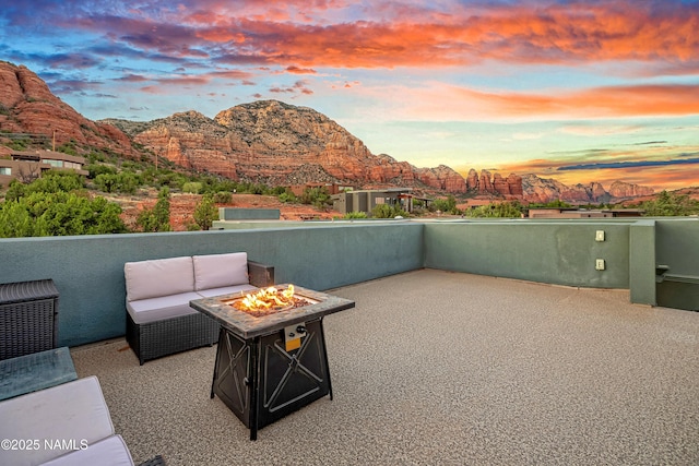 patio terrace at dusk featuring an outdoor fire pit and a mountain view