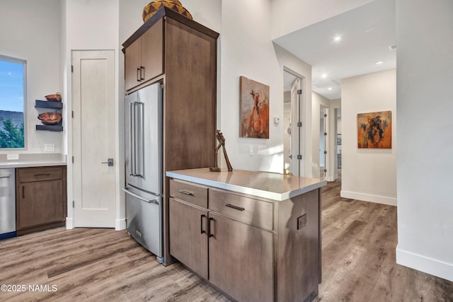 kitchen featuring stainless steel appliances, light countertops, light wood finished floors, and baseboards