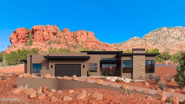 view of front facade with a garage, a mountain view, a chimney, and stucco siding