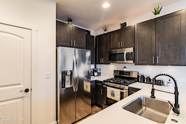 kitchen featuring dark brown cabinets, a sink, light countertops, stainless steel appliances, and wood finished floors