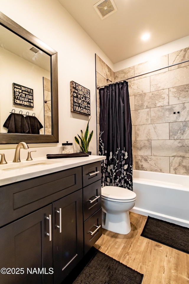 full bathroom featuring visible vents, vanity, wood finished floors, toilet, and shower / bath combo