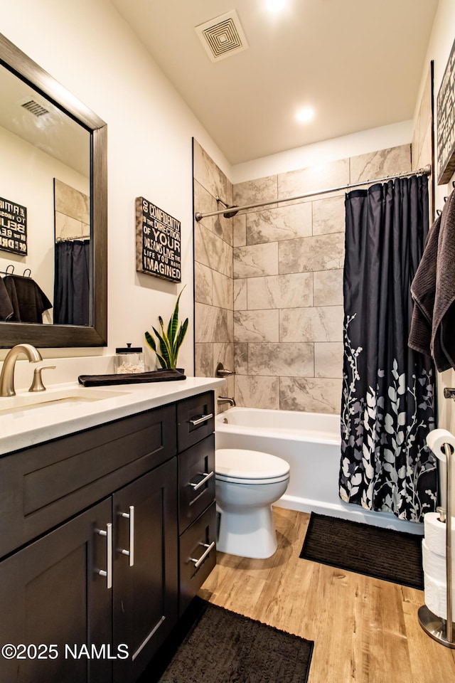 full bath featuring visible vents, vanity, wood finished floors, toilet, and shower / bathtub combination with curtain
