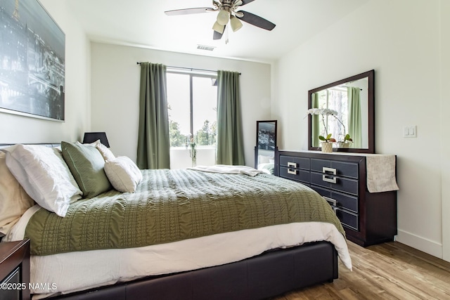 bedroom featuring visible vents, baseboards, ceiling fan, and wood finished floors
