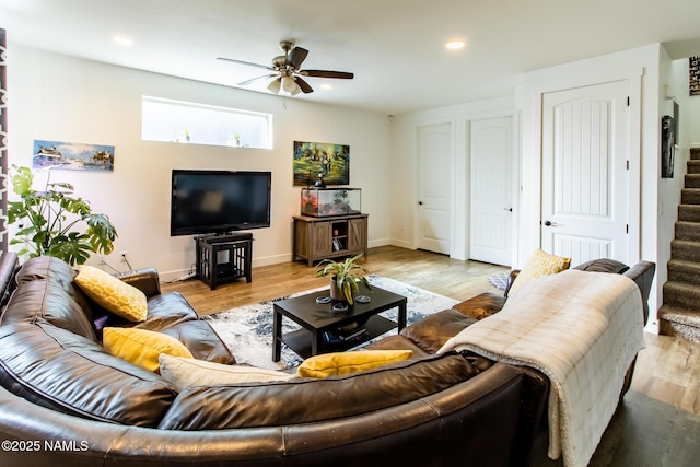 living room featuring ceiling fan, stairs, baseboards, recessed lighting, and light wood-style flooring