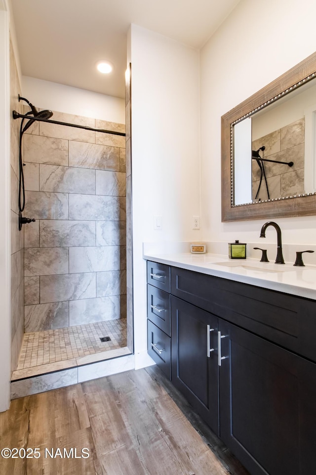 bathroom with vanity, wood finished floors, and a tile shower