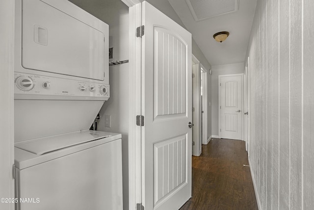 laundry room featuring stacked washer / dryer, laundry area, dark wood-type flooring, and visible vents