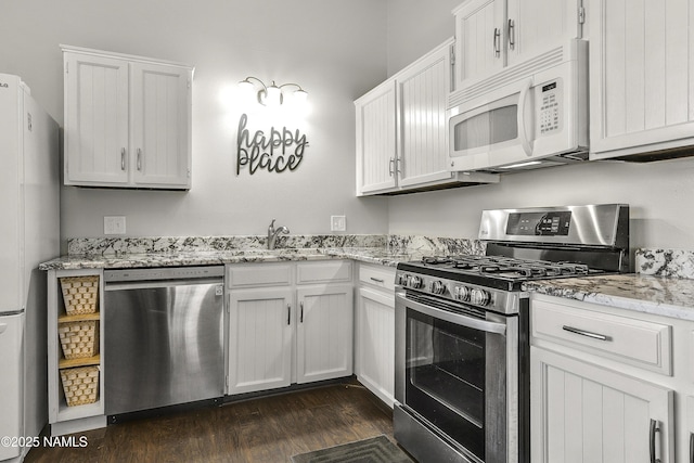 kitchen featuring light stone countertops, a sink, dark wood-type flooring, appliances with stainless steel finishes, and white cabinetry