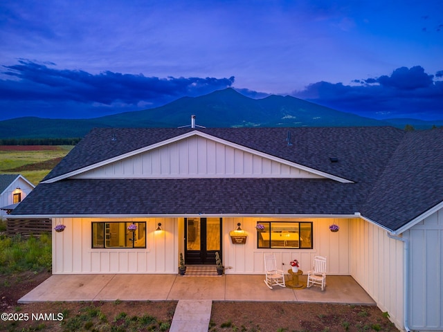 6552 Kelsey Springs Way, Flagstaff, AZ 86001 - view of front of house featuring a shingled roof, a patio, board and batten siding, and a mountain view