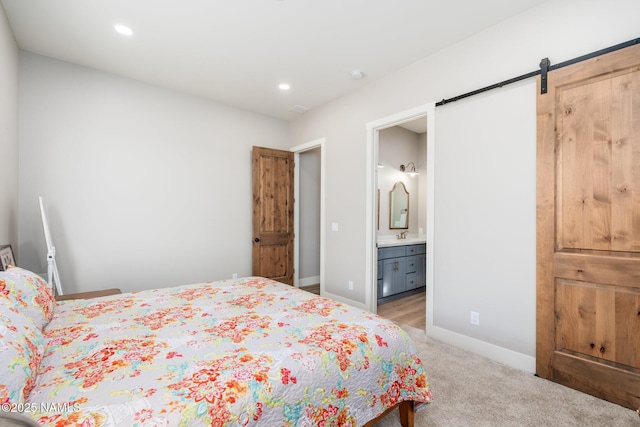 6552 Kelsey Springs Way, Flagstaff, AZ 86001 - bedroom with baseboards, light colored carpet, a barn door, recessed lighting, and ensuite bathroom