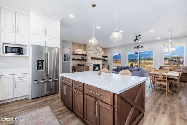 6552 Kelsey Springs Way, Flagstaff, AZ 86001 - kitchen featuring high end refrigerator, built in microwave, a fireplace, white cabinetry, and light wood finished floors