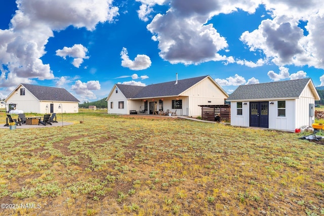 6552 Kelsey Springs Way, Flagstaff, AZ 86001 - rear view of house featuring an outbuilding, a patio, a lawn, board and batten siding, and a fire pit