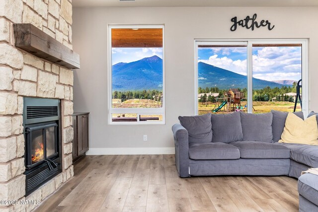 6552 Kelsey Springs Way, Flagstaff, AZ 86001 - living area with a mountain view, light wood-type flooring, a stone fireplace, and baseboards