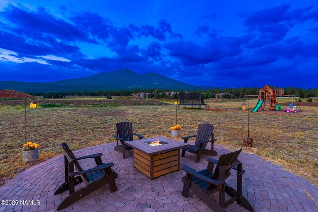 6552 Kelsey Springs Way, Flagstaff, AZ 86001 - view of patio featuring a trampoline, a fire pit, a mountain view, and a playground