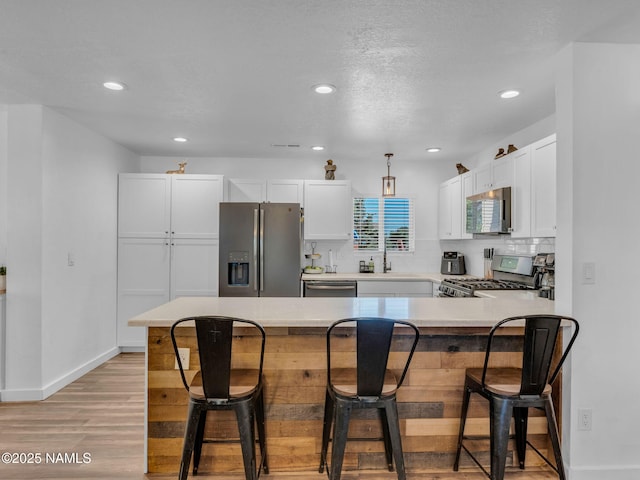7776 Moonbeam Dr, Flagstaff, AZ 86004 - kitchen featuring stainless steel appliances, light wood-type flooring, a breakfast bar, white cabinets, and recessed lighting
