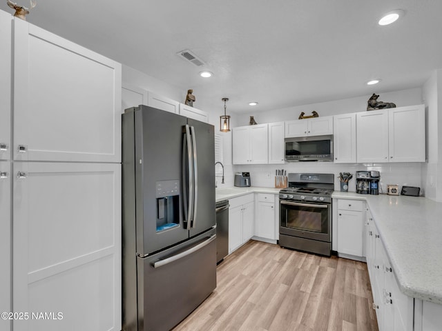 7776 Moonbeam Dr, Flagstaff, AZ 86004 - kitchen featuring appliances with stainless steel finishes, white cabinets, backsplash, recessed lighting, and light wood-style floors