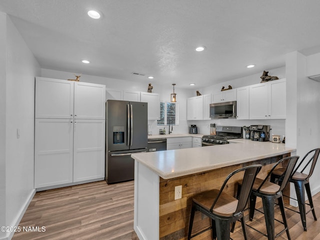 7776 Moonbeam Dr, Flagstaff, AZ 86004 - kitchen featuring appliances with stainless steel finishes, light wood-type flooring, a peninsula, a kitchen breakfast bar, and light countertops