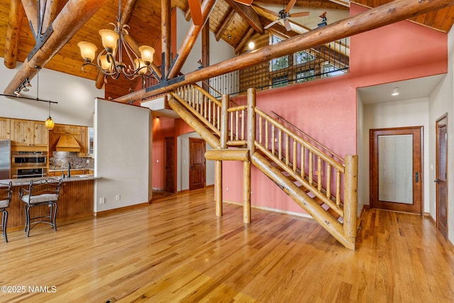 4536 Brackin Ranch Rd, Flagstaff, AZ 86001 - unfurnished living room featuring high vaulted ceiling, stairway, light wood-style floors, a chandelier, and wood ceiling with exposed beams