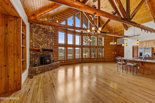 4536 Brackin Ranch Rd, Flagstaff, AZ 86001 - unfurnished living room with a chandelier, high vaulted ceiling, wooden ceiling with exposed beams, light wood-type flooring, and log walls
