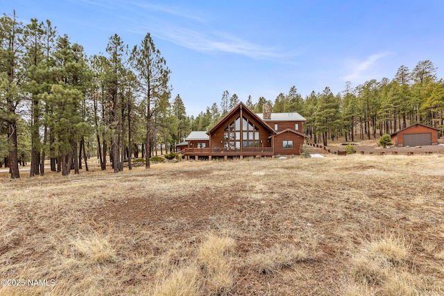 4536 Brackin Ranch Rd, Flagstaff, AZ 86001 - rear view of property featuring a chimney, a wooden deck, faux log siding, metal roof, and a garage
