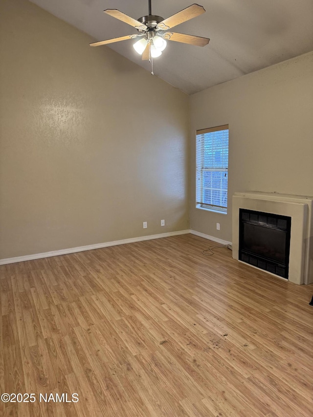 unfurnished living room with a ceiling fan, vaulted ceiling, a fireplace, and light wood finished floors