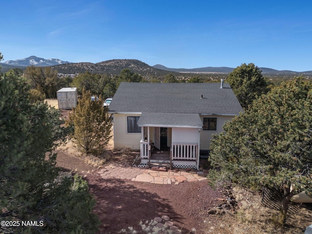 rear view of property featuring a shingled roof and a mountain view