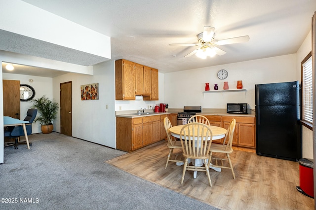 kitchen with sink, ceiling fan, black appliances, light carpet, and a textured ceiling