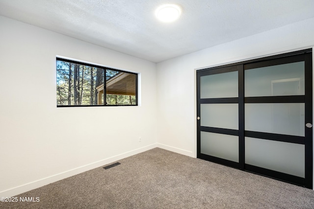 spare room featuring carpet floors and a textured ceiling