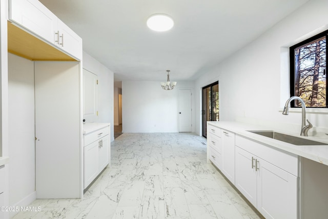 kitchen featuring sink, white cabinets, an inviting chandelier, and decorative light fixtures