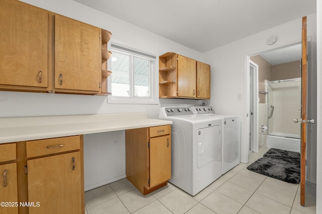 laundry area with cabinet space, independent washer and dryer, and light tile patterned floors