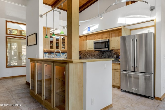 kitchen with light brown cabinetry, appliances with stainless steel finishes, high vaulted ceiling, and backsplash